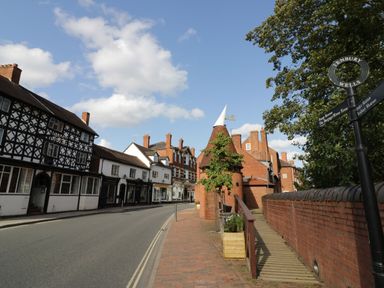 A street with brick buildings and a timber-framed house with a road sign in Tenbury Wells