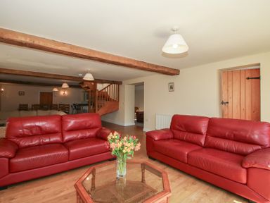 A living room with red sofas and a coffee table at The Wainhouse in Bockleton near Tenbury Wells