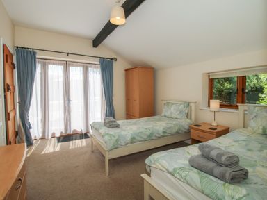 A bedroom with two beds and a wardrobe at The Wainhouse in Bockleton near Tenbury Wells