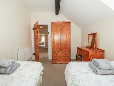 A bedroom with two beds and a wardrobe at The Wainhouse in Bockleton near Tenbury Wells