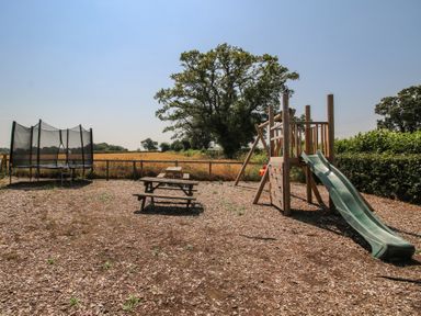 An outdoor play area with a slide and trampoline at The Wainhouse Bockleton near Tenbury Wells