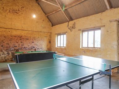 A game room with a ping pong table and a pool table against stone walls at The Old Bakery in Crowcombe