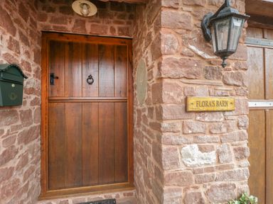 A wooden door on a stone wall with a mailbox and a lantern at Floras Barn in Crowcombe