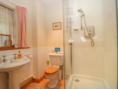 A bathroom with a pedestal sink, a toilet with a wooden seat, and a shower cubicle at Floras Barn in Crowcombe