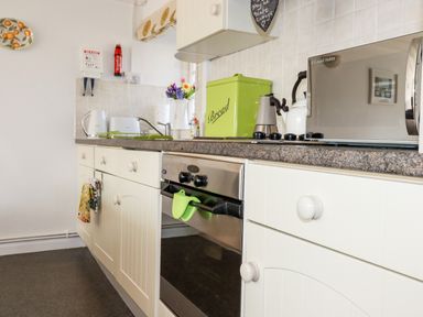 A kitchen with cabinets oven microwave and a green bread box at Slate Cottage in Tredethy near Bodmin Moor