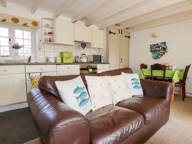 A kitchen and dining area with a brown leather sofa and cushions at Slate Cottage in Tredethy near Bodmin Moor