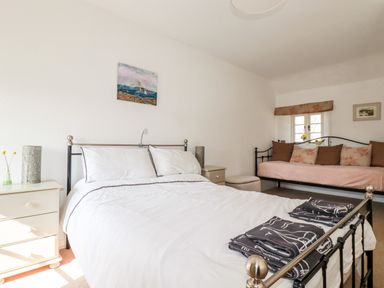 A bedroom with a double bed white bedding and folded towels and a daybed with cushions at Slate Cottage Tredethy near Bodmin Moor