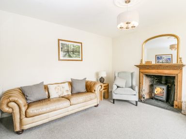 A living room with a leather sofa armchair fireplace and a large mirror at Viaduct House in Lydbrook