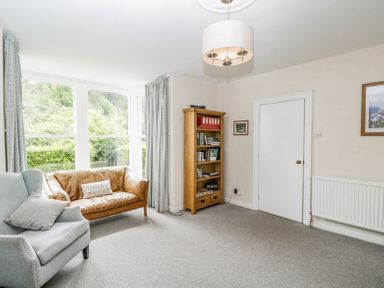 A living room with a leather sofa a fabric armchair a bookshelf and a door at Viaduct House in Lydbrook