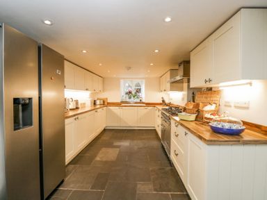 A kitchen with white cabinets wooden countertops a stainless steel refrigerator and a window at Viaduct House in Lydbrook