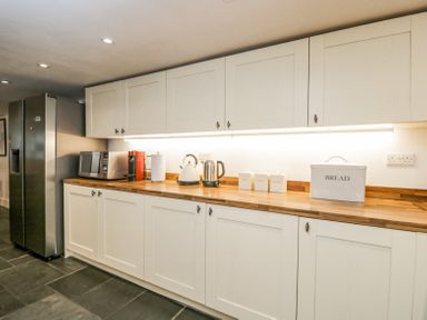 A kitchen with white cabinets stainless steel refrigerator microwave coffee machine kettle and bread box at Viaduct House in Lydbrook