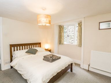 A bedroom with a wooden bed frame and bedside table with lamp at Viaduct House in Lydbrook