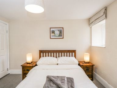 A bedroom with a double bed white bedding two bedside tables with lamps and a framed picture on the wall at Viaduct House in Lydbrook