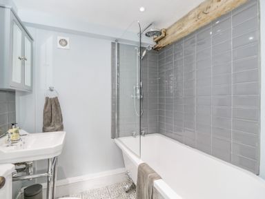 A bathroom with a bathtub shower combination and a sink with mirror cabinet at Viaduct House in Lydbrook