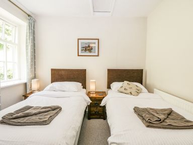 A bedroom with two single beds a wooden nightstand and a window at Viaduct House in Lydbrook