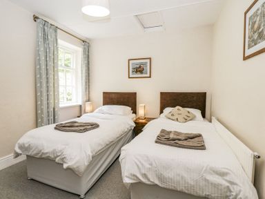 A bedroom with two single beds bedside lamps and pictures on the walls at Viaduct House in Lydbrook