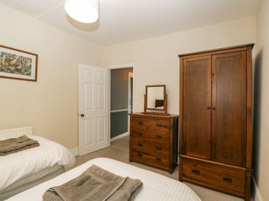 A bedroom with two single beds with towels on them a wooden dresser with mirror and a wooden wardrobe at Viaduct House in Lydbrook