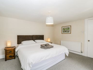 A bedroom with a double bed white bedding wooden bedside tables and lamps at Viaduct House in Lydbrook