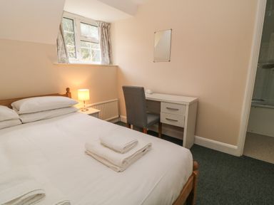 A bedroom with a bed a desk chair lamp and folded towels at Aldrich Cottage Radstock