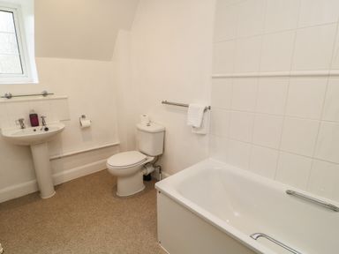 A bathroom with a bathtub sink toilet towel rail and a window at Aldrich Cottage Radstock