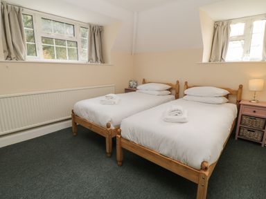 A bedroom with two single beds and folded towels on them at Aldrich Cottage in Radstock