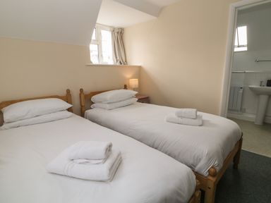 A bedroom with two single beds and folded towels near a window at Aldrich Cottage Radstock