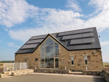 A stone building with large glass window and solar panels on the roof at West Gate in Embleton