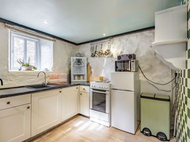 A kitchen with white cabinets a stove a refrigerator a microwave and a sink at Celyn Farm Cottage in Deiniolen near Llanberis