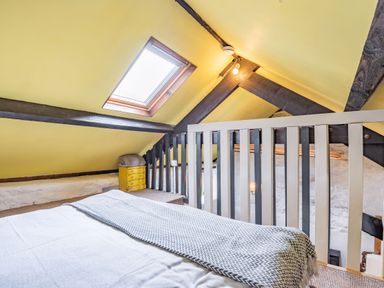 An attic bedroom with a bed a skylight and a yellow chest of drawers at Celyn Farm Cottage Deiniolen near Llanberis