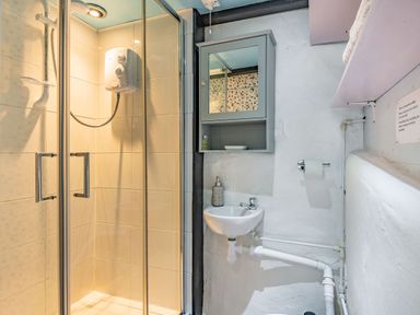 A bathroom with a shower enclosure sink cabinet with mirror and shelves at Celyn Farm Cottage in Deiniolen near Llanberis