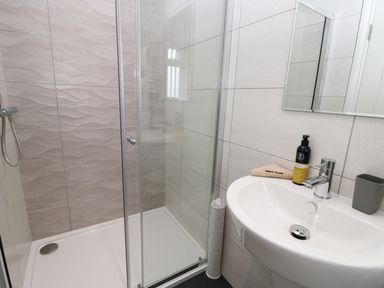A bathroom with a shower enclosure sink mirror and toiletries at The Office Gardens Apartment 2 in Whitby