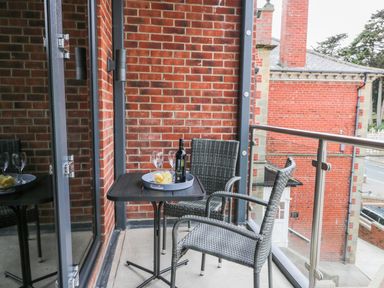 A small balcony with a table and two chairs with a wine bottle and glasses at The Office Gardens Apartment 2 in Whitby