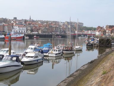 A harbor with boats docked on the water and buildings in the background at The Office Gardens Apartment 2 Whitby