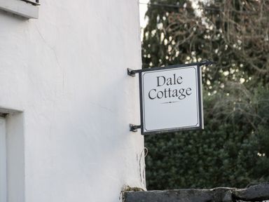 A white wall with a hanging sign that reads Dale Cottage with trees in the background at Dale Cottage in Llanrwst