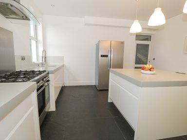 A kitchen with a stove sink refrigerator island and pendant lights at Dale Cottage in Llanrwst