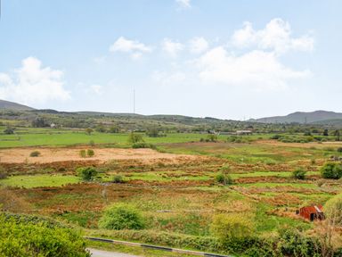 A rural landscape with fields trees and hills under a blue sky at Pen Y Graig in Talysarn