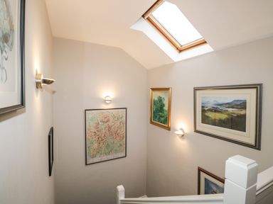 A stairwell with framed pictures on the walls and a skylight window at Rothay 17 in Ambleside