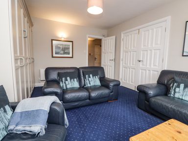 A sitting room with leather sofas and a wooden table at Rothay 17 in Ambleside