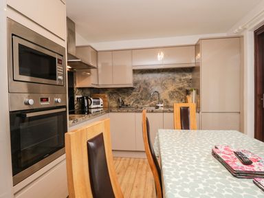 A kitchen with built in microwave and oven wooden chairs and a dining table at Rothay 17 in Ambleside