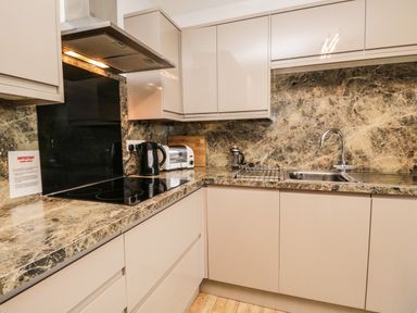 A kitchen with a stove kettle toaster sink and marble countertops at Rothay 17 Ambleside