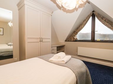 A bedroom with a bed folded towels wardrobe mirror and a window with curtains at Rothay 17 in Ambleside