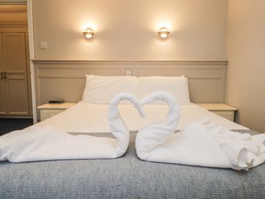 A bed with white pillows and towels folded into swans on a blanket in a bedroom at Rothay 17 in Ambleside