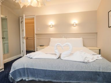A bedroom with a bed with two towel swans folded on it and bedside tables at Rothay 17 in Ambleside