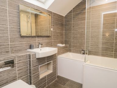 A bathroom with a sink toilet and bathtub with glass screen at Rothay 17 in Ambleside