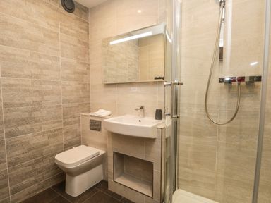 A bathroom with a toilet sink mirror and glass shower at Rothay 17 Ambleside