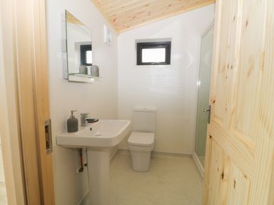 A bathroom with a sink soap dispenser toilet mirror and a shower at Hayfields in Grimston