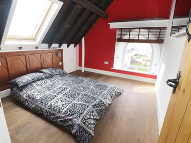 A bedroom with a low bed covered in patterned bedding under a slanted ceiling with a skylight at No 1 Church Cottages in Llanelli