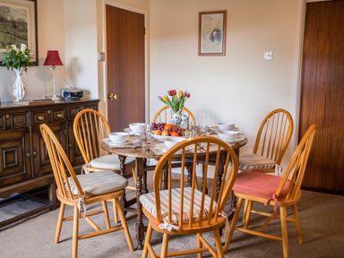 A dining room with round wooden table set for six and wooden chairs at Shepherds Retreat in Gortin