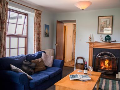 A living room with a blue sofa and wooden coffee table in front of a fireplace at Shepherds Retreat in Gortin