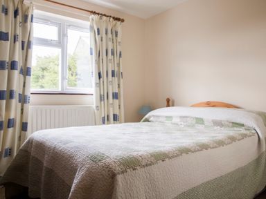 A bedroom with a double bed a window with curtains and a bedside lamp at Shepherds Retreat in Gortin